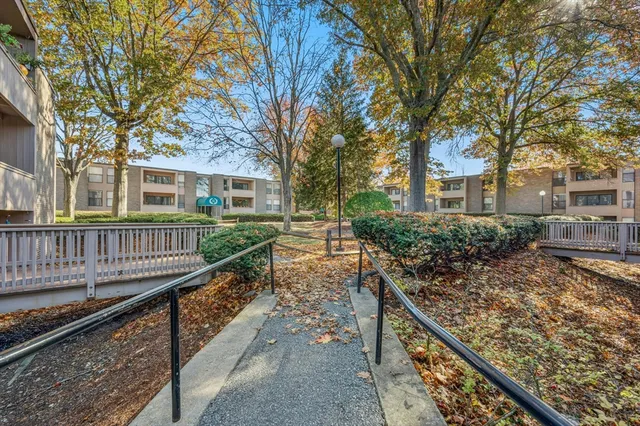 a view of a house with large trees and wooden fence