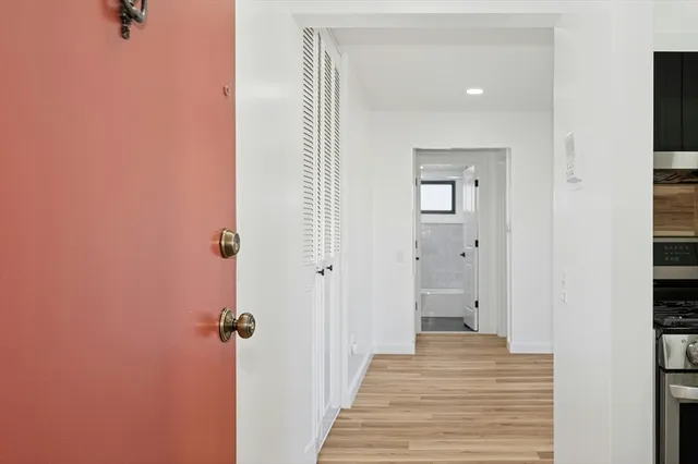 a view of a hallway with a closet and wooden floor