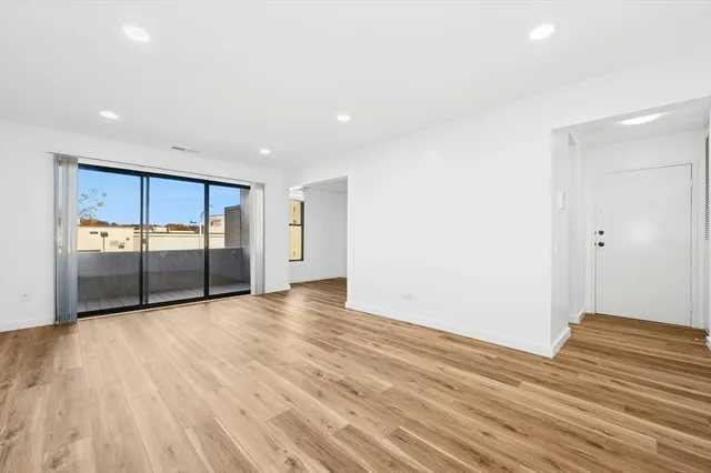 a view of an empty room with wooden floor and closet