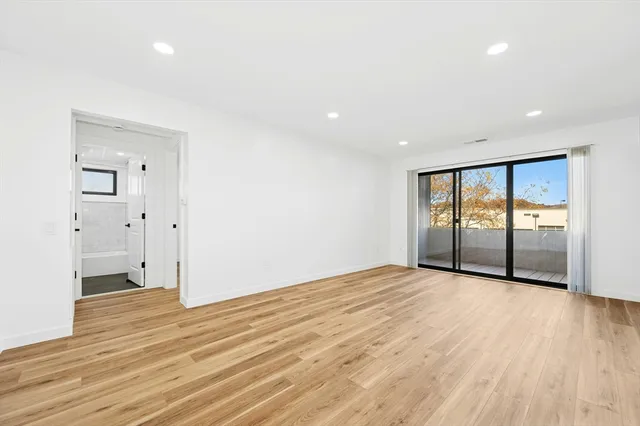 a view of an empty room with wooden floor and closet
