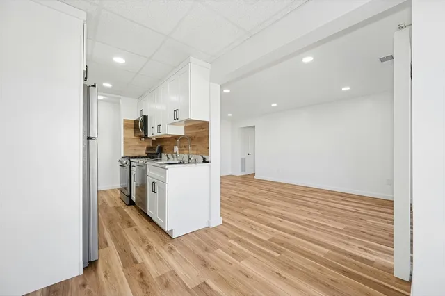 a view of kitchen with kitchen island wooden floor cabinets and stainless steel appliances
