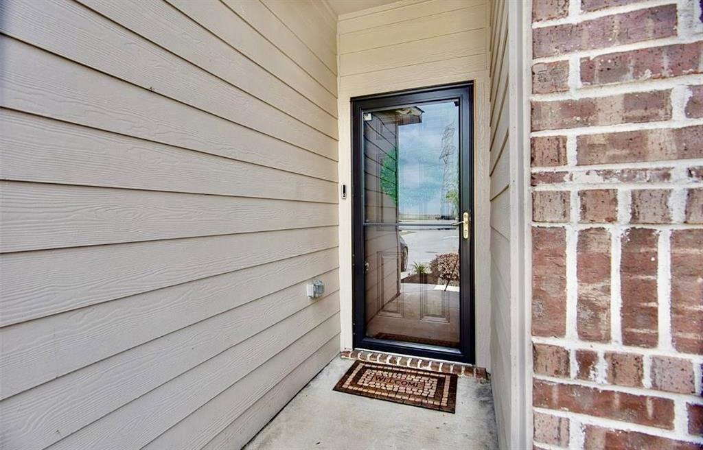 111 Rebel Road Venus, TX 76084 - Photo 2 of 7 Entryway featuring a storm door with a full-view glass panel, a concrete porch, light-colored horizontal siding, and a brick exterior accent wall