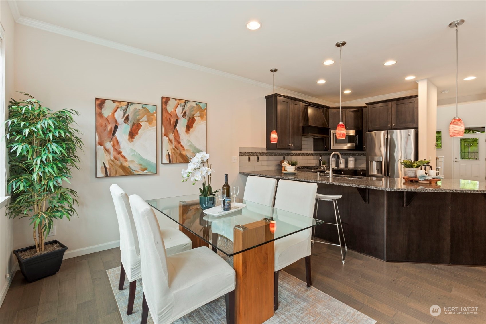 19529 34th Drive Southeast Bothell, WA 98012 - Photo 10 of 38 a kitchen with stainless steel appliances kitchen island granite countertop a refrigerator a stove a microwave oven with a dining table and chairs with wooden floor