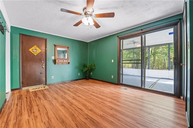 a view of an empty room with a window and wooden floor