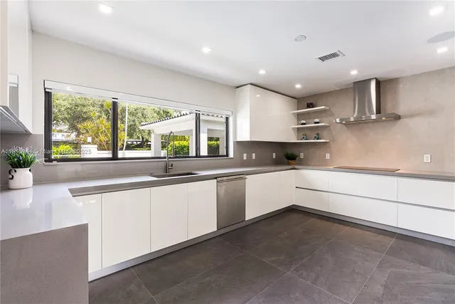 a large kitchen with stainless steel appliances a large counter top a stove a chimney a sink and a large window