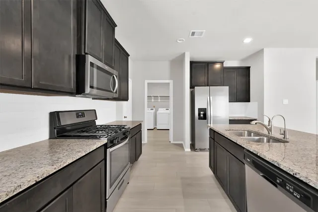 a kitchen with stainless steel appliances granite countertop a sink stove microwave and refrigerator