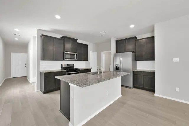 a large kitchen with stainless steel appliances granite countertop a stove a sink and a refrigerator