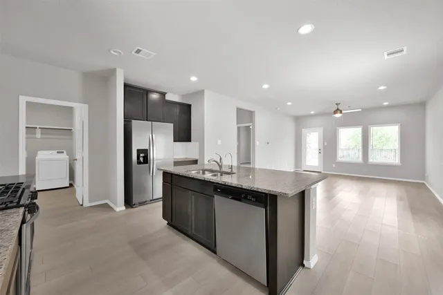 a kitchen with stainless steel appliances granite countertop a refrigerator a sink dishwasher a stove and a refrigerator with wooden floor