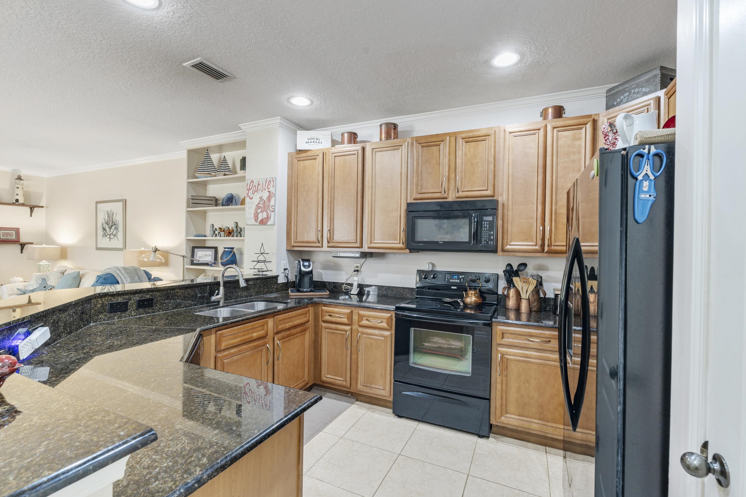 110 Magnolia Crossing Point, Unit 1901 St. Augustine, FL 32086 - Photo 33 of 38 Kitchen with black appliances, open floor plan, dark stone counters, ornamental molding, and wood finish cabinetry