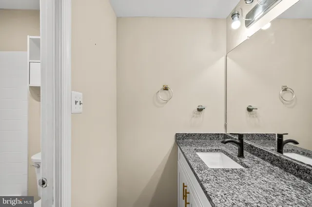 a bathroom with a granite countertop sink and a mirror