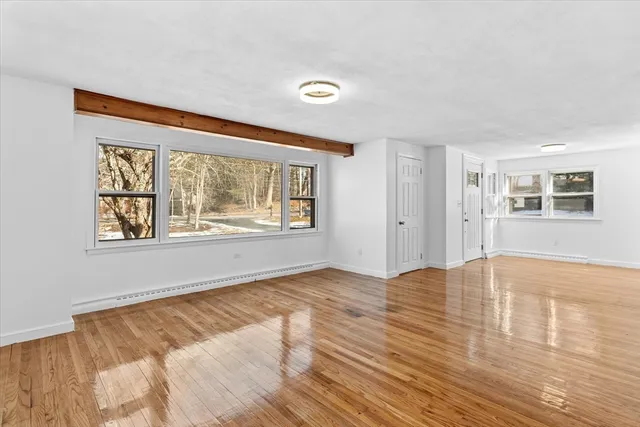a view of an empty room with window and wooden floor