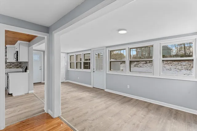 a view of an empty room with window and wooden floor