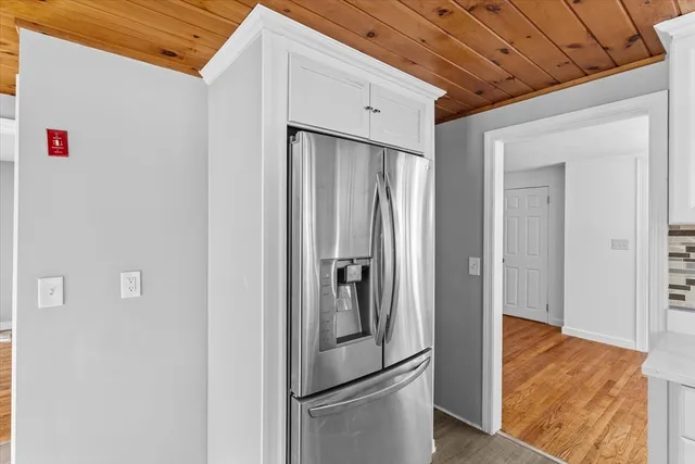 a view of a refrigerator in kitchen and an empty room