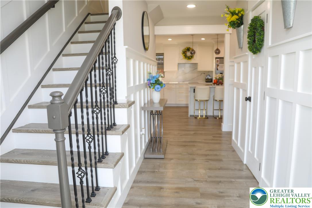 1412 Stanford Road Bethlehem, PA 18018 - Photo 5 of 58 A graceful staircase with intricate iron balusters ascends from the warm, wood-toned flooring of this inviting entry, leading into a bright, modern kitchen.