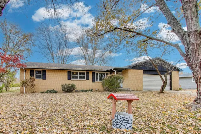 a backyard of a house with table and chairs under an umbrella