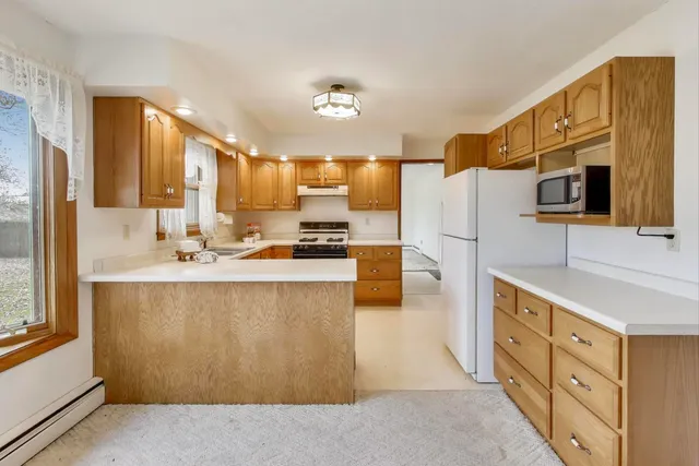 a kitchen with stainless steel appliances kitchen island granite countertop a refrigerator a stove and a sink with large window