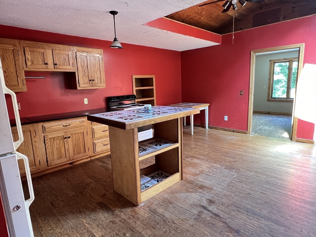 380 Lower Hampden Road Monson, MA 01057 - Photo 27 of 42 a kitchen with stainless steel appliances granite countertop a stove top oven a dining table and chairs with wooden floor