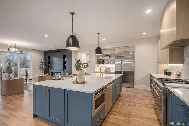 a large kitchen with kitchen island a stove a sink a refrigerator and a dining table with wooden floor