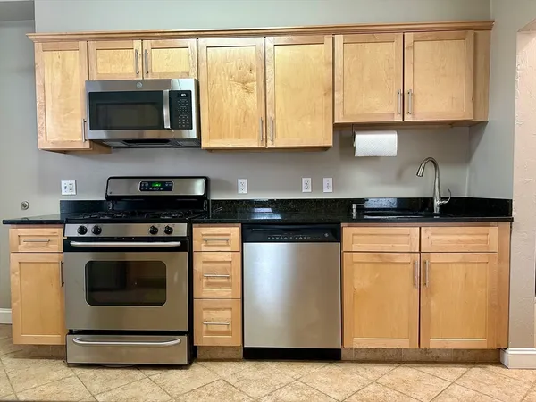a kitchen with stainless steel appliances granite countertop a stove a sink and a microwave