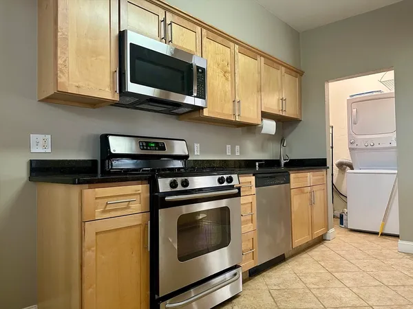 a kitchen with stainless steel appliances granite countertop white cabinets a stove a microwave and a refrigerator