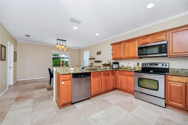 a kitchen with stainless steel appliances granite countertop a stove top oven a sink dishwasher a dining table and chairs with wooden floor