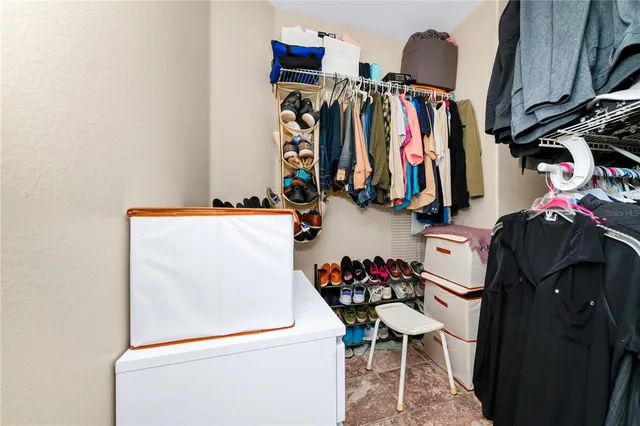 a view of walk in closet with clothes and shoes