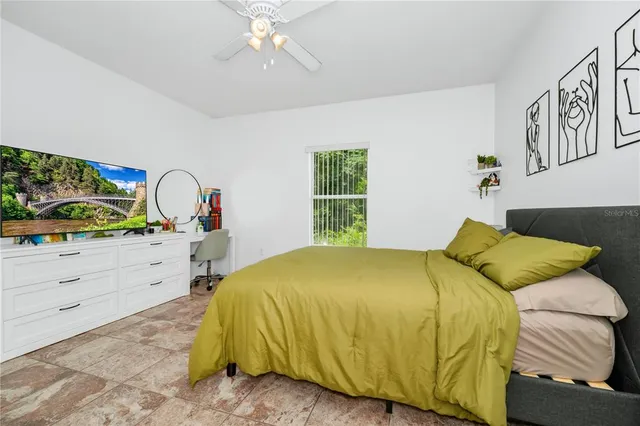 a bedroom with a bed a computer on a desk and a chair