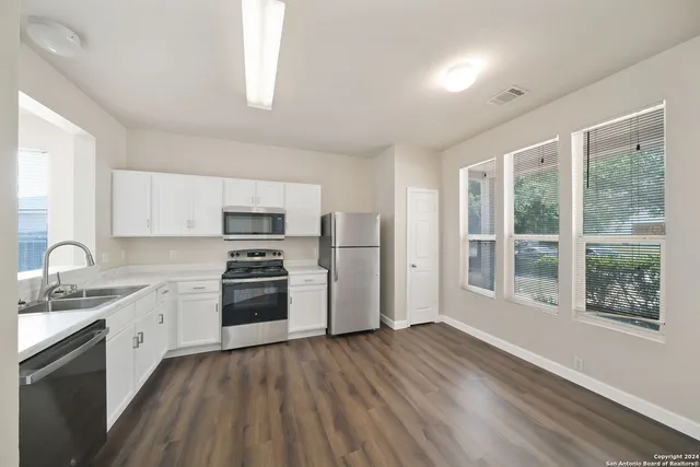 a kitchen with a sink wooden floor and stainless steel appliances