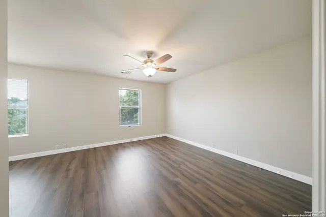 an empty room with wooden floor and windows