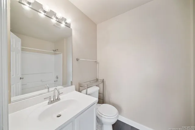 a bathroom with a sink mirror vanity and toilet