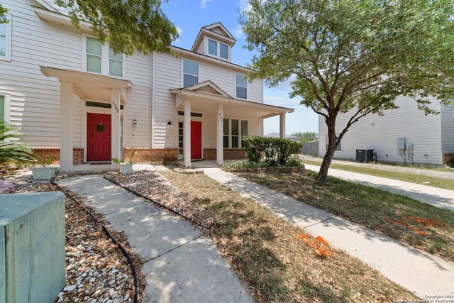 a front view of a house with a yard and large tree