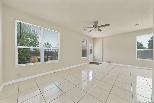 a view of an empty room with a window and kitchen chandelier