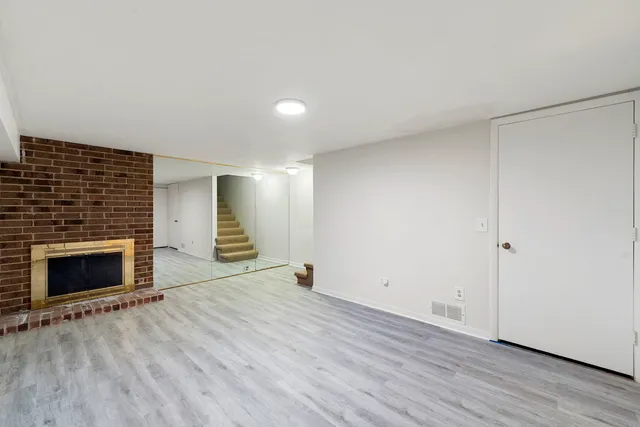 a view of empty room with wooden floor and fireplace
