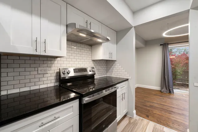 a kitchen with granite countertop cabinets a stove and a wooden floor