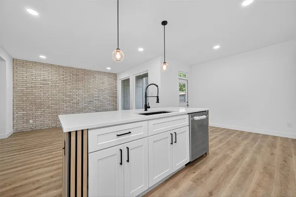 a kitchen with stainless steel appliances a sink a white wooden cabinets and a wooden floor