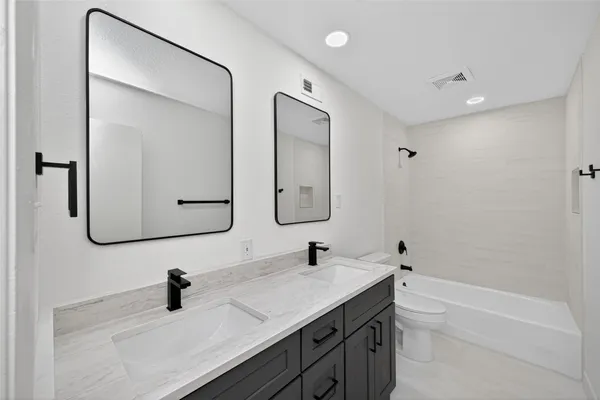 a bathroom with a double vanity sink double mirror and bathtub
