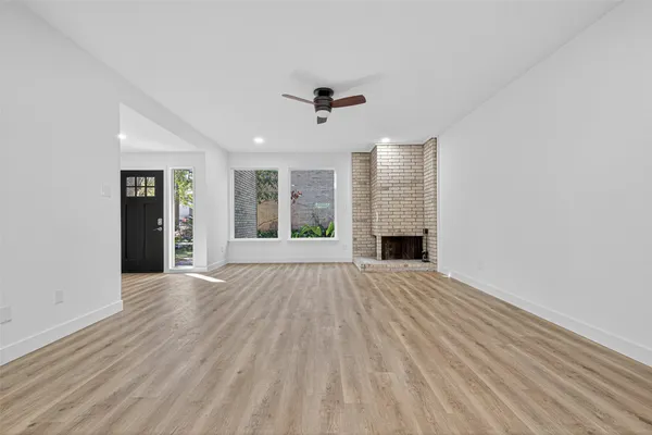 an empty room with windows and fireplace