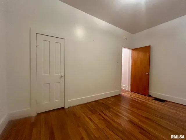 a view of an empty room with wooden floor and closet