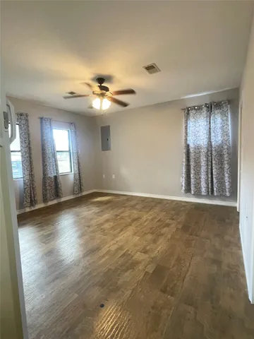 an empty room with wooden floor and windows