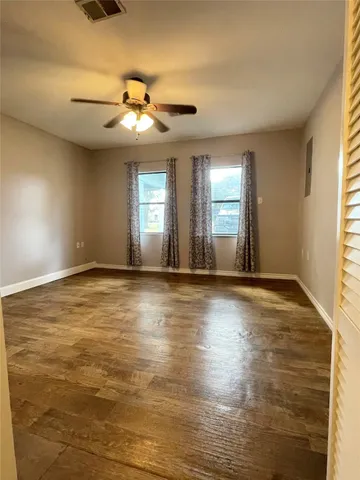 a view of an empty room with window and wooden floor