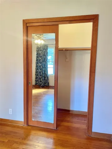 an empty room with wooden floor closet and windows