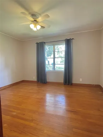 a view of an empty room with window and wooden floor