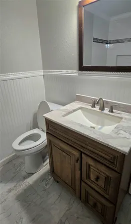 a bathroom with a granite countertop toilet sink and mirror