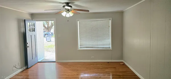 a view of an empty room with window chandelier fan and fire place