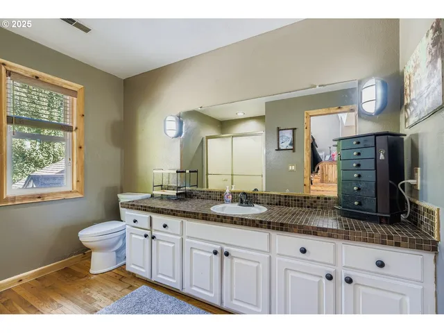 a bathroom with a granite countertop sink toilet and mirror