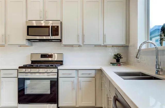 a kitchen with stainless steel appliances granite countertop a sink a stove a microwave and cabinets