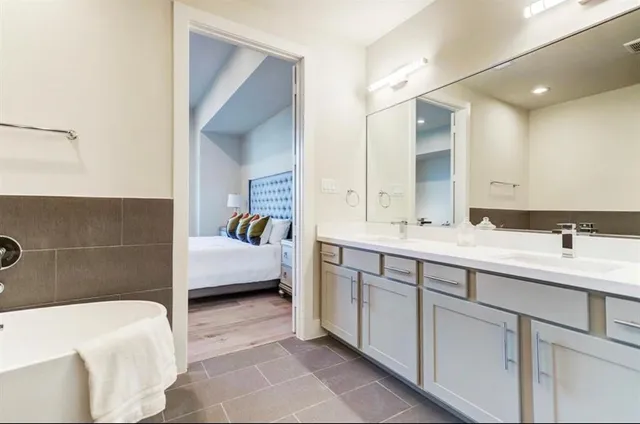 a en suite bathroom with a double vanity sink a mirror and a bathtub