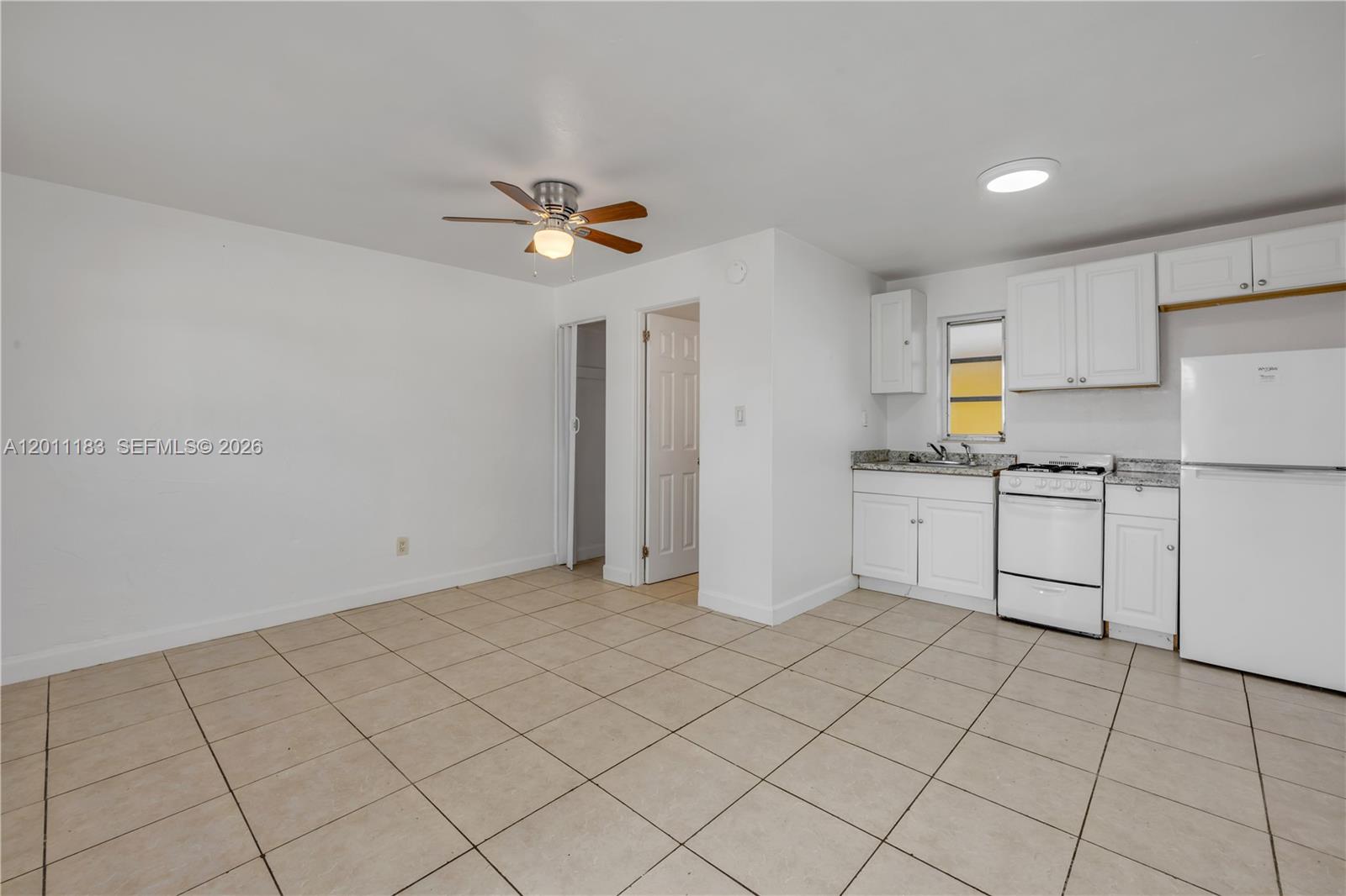 1208 South Ridgewood Avenue Daytona Beach, FL 32114 - Photo 13 of 27 a kitchen with white cabinets a sink appliances and a window