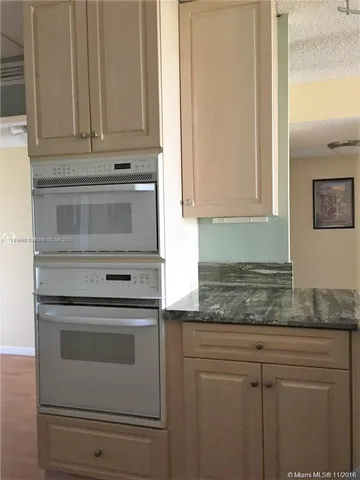 a kitchen with granite countertop white cabinets and stainless steel appliances