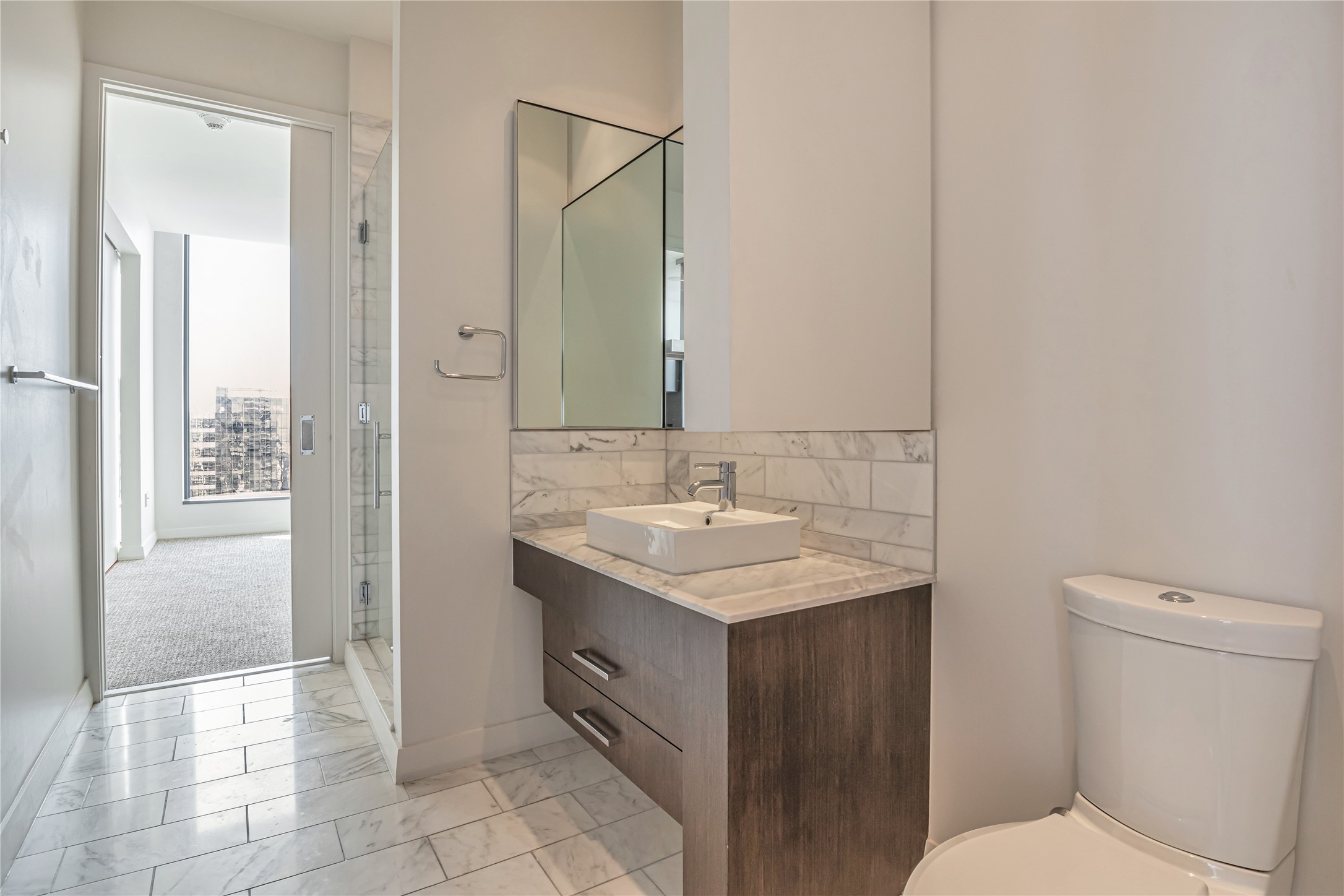 210 Lavaca Street, Unit 2903 Austin, TX 78701 - Photo 20 of 39 Guest Bathroom #2 featuring vanity, tasteful backsplash, toilet, marble finish floor, and a stall shower